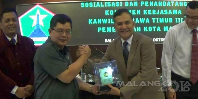 Sekda Kota Malang Dr. Idrus Achmad, M.Si (kiri) menerima cenderamata dari Kepala Kanwil DJP Jatim III Rudy Gunawan Bastari